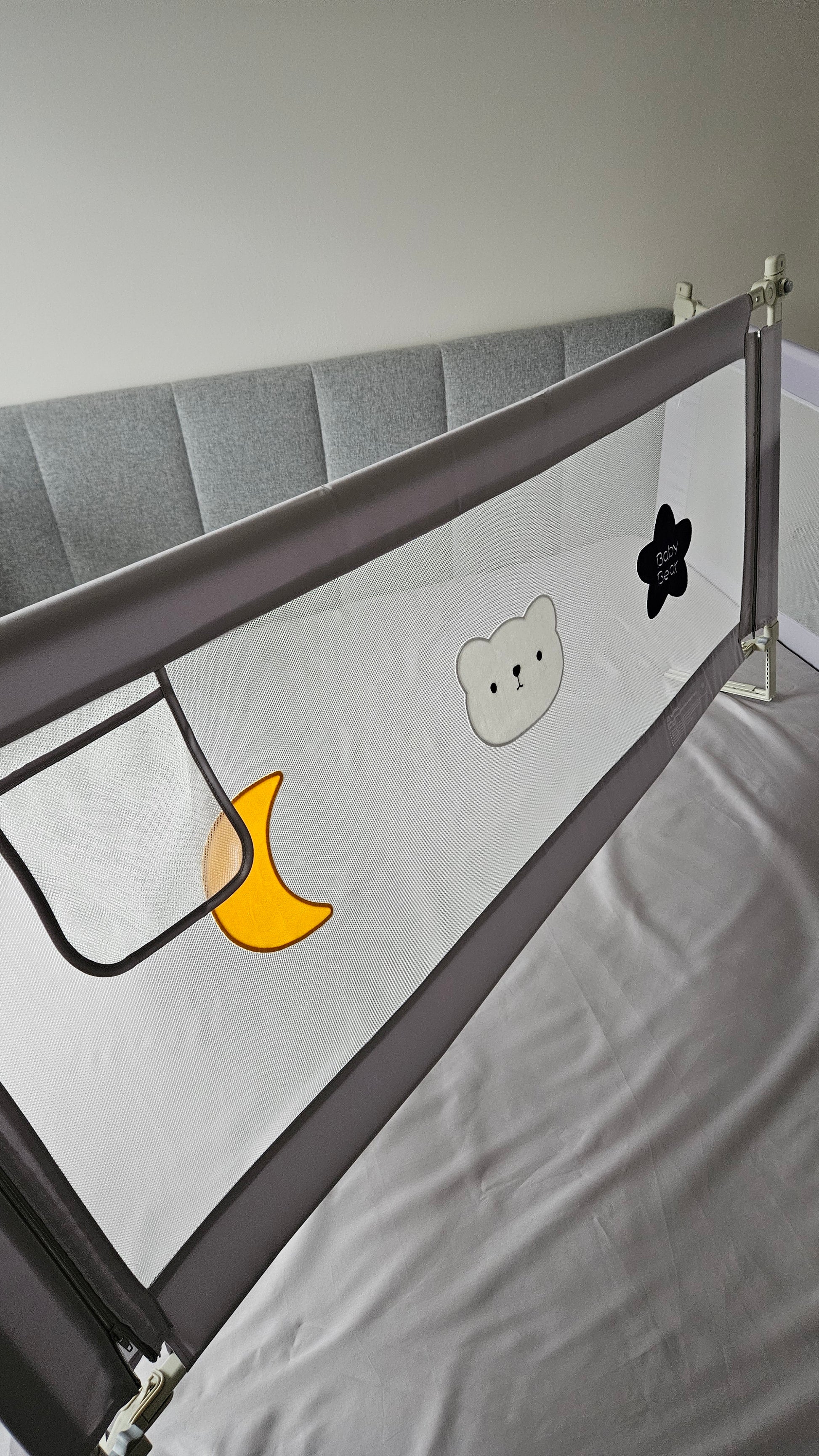 Gray baby bed rail guard with mesh panel and cute bear, moon, and star designs
