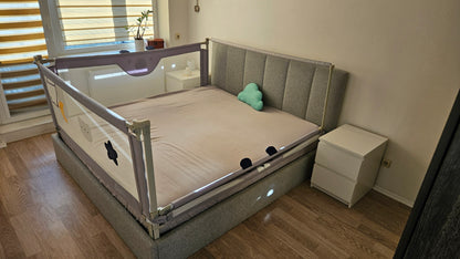 Modern bedroom with a grey upholstered bed, safety bed rails, and a small blue cloud pillow